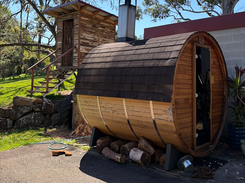 Barrel sauna, firewood stacked underneath